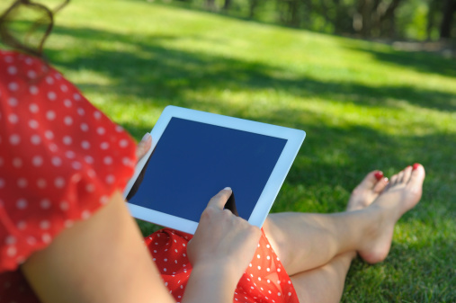 Woman using digital tablet in park.