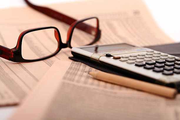 A close-up of papers, glasses and a calculator stock photo