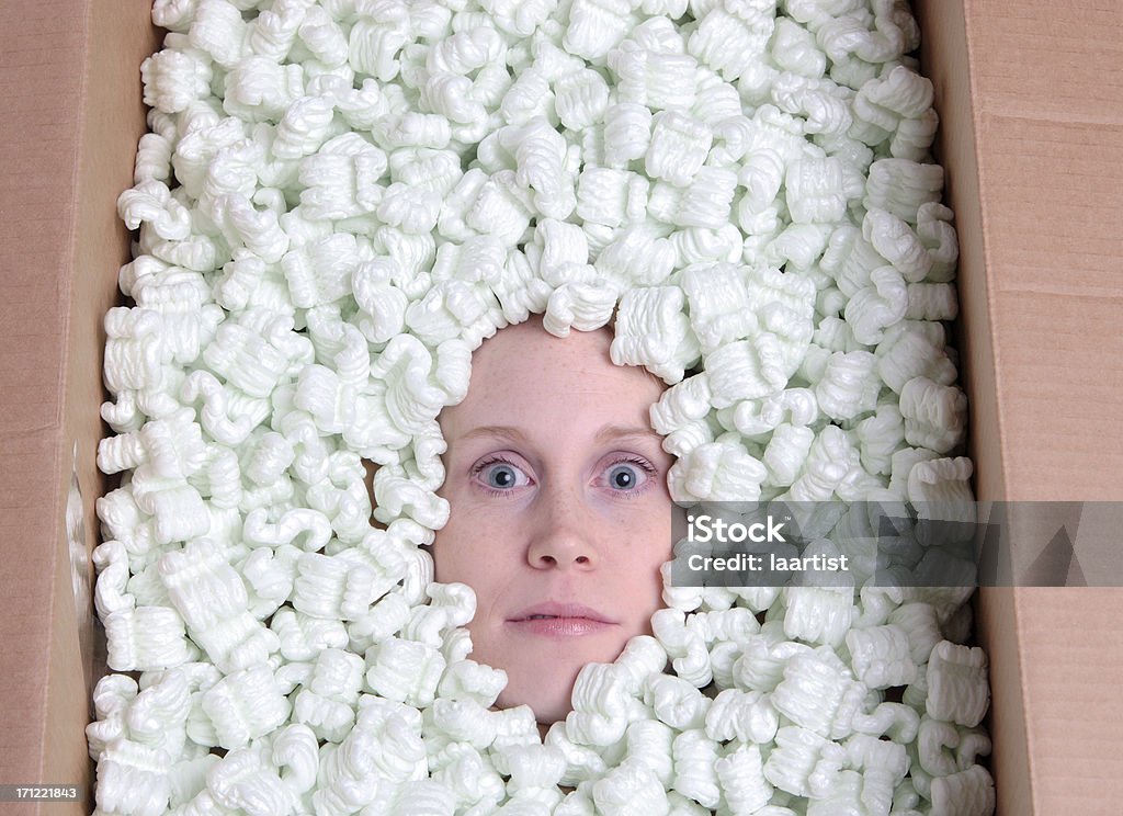 Staring. Concept image of a freaky head burried in a box of packaging peanuts. Bizarre Stock Photo