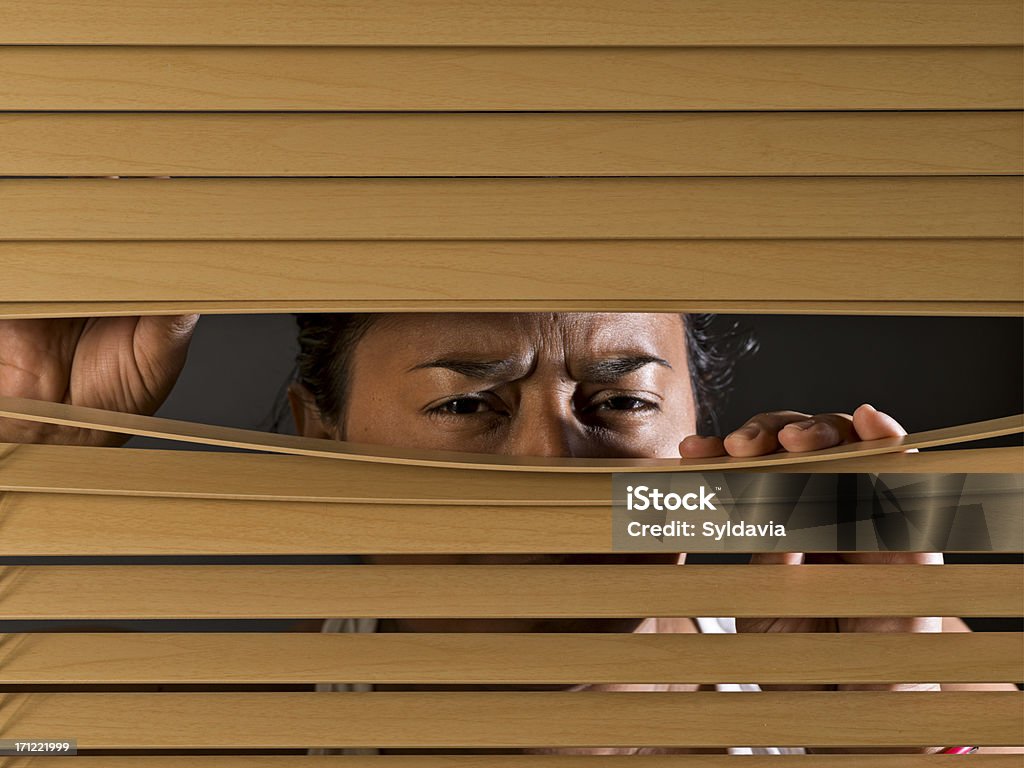 Spying Black woman spying on something through venetian blinds Neighbor Stock Photo