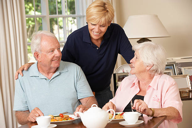 年配のカップルとご一緒にお楽しみになりながらのお食事で、ご自宅 carer - senior adult nursing home eating home interior ストックフォトと画像