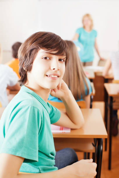 istock Preteen boy sitting in class, turning to camera 171223767