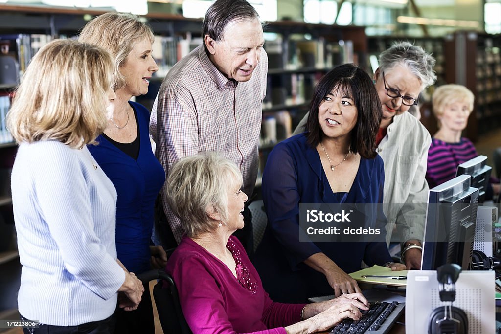 Grupo de ejecutivos Aprenda con la computadora en la biblioteca - Foto de stock de Indicar libre de derechos