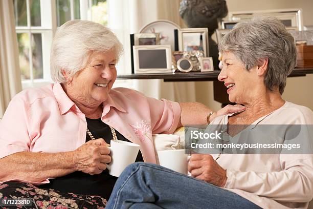 Two Retired Senior Female Friends Sitting On Sofa Stock Photo - Download Image Now - Drinking, Friendship, Senior Adult