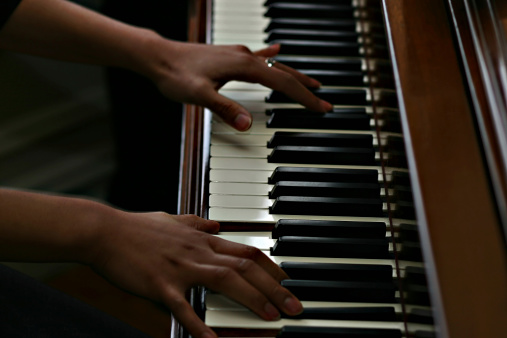 African american hands playing a piano. Keys in sharp focus - slight motion blur on arms.
