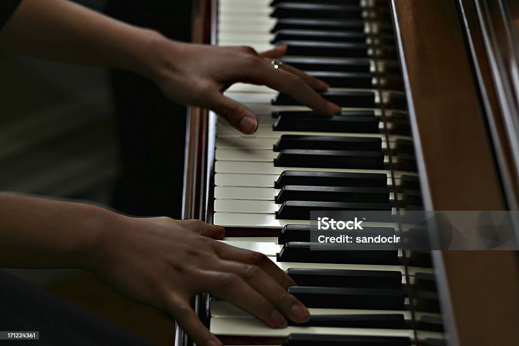 plan African american hands playing a piano. Keys in sharp focus - slight motion blur on arms. Piano Stock Photo