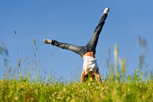 Young woman doing cartwheel on grass during beautiful spring day