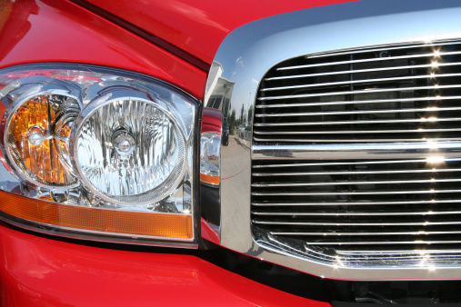 Front headlight and grill of a sporty red truck. 