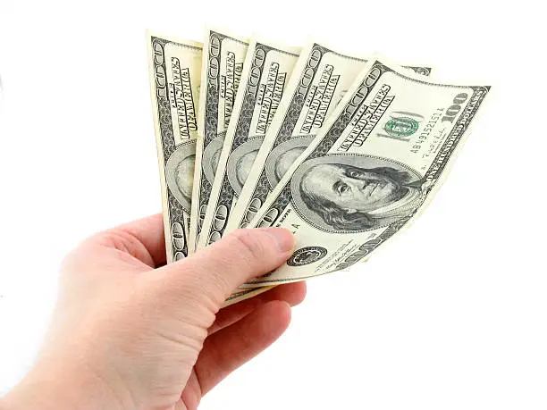 A female hand holding five $100 bills.