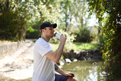 Athlete man drinking from aluminum water bottle.