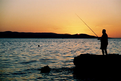A man fishing during sunset.