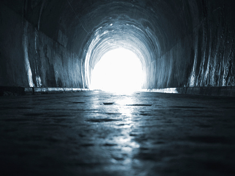 A tunnel with a bright light at the end. Tinted blue