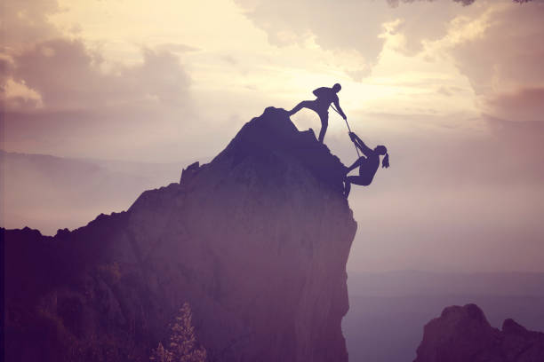 Men helping his friend hiker climb up the hill
