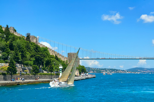 Sailboat, ancient fortress on the shore and bridge View of the Bosphorus Strait. Turkey. Istanbul.