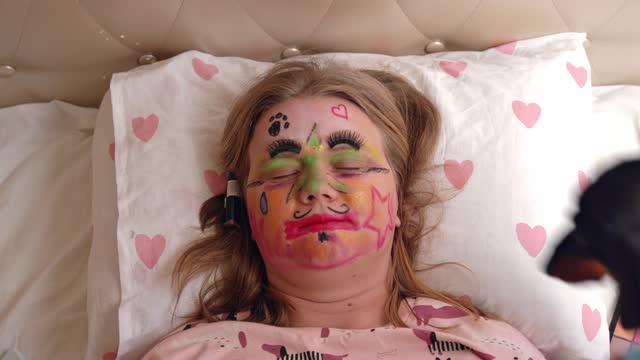 Two dogs paint face cosmetics of sleeping woman April fool children prank makeup