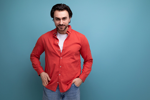 well-groomed caucasian brunette 30s man in a red shirt on a background with copy space.