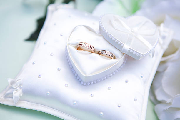 Wedding Rings Close-up of white heart-shaped jewelry box with a wedding rings and white flowers in the background. jewelry box photos stock pictures, royalty-free photos & images