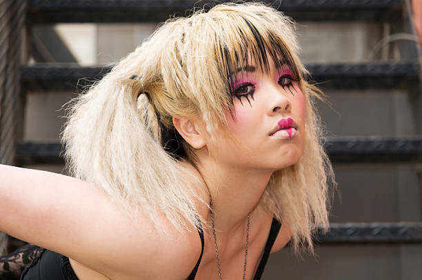 Horizontal outdoors shot of blonde Asian teen in wild makeup.