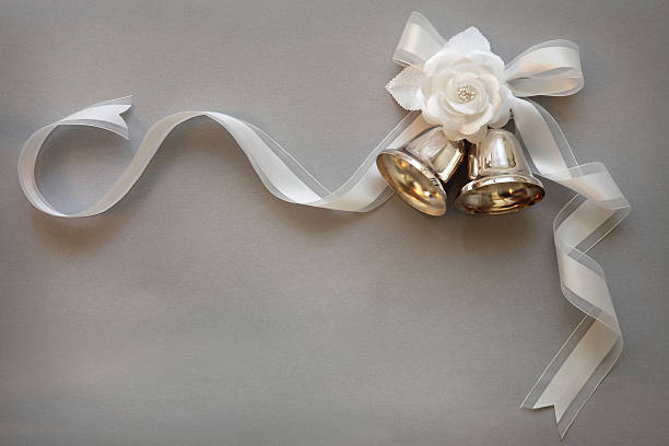 Wedding Bells Silver wedding bells tied with a white ribbon and adorned with pearls and flowers on a silver background bell photos stock pictures, royalty-free photos & images