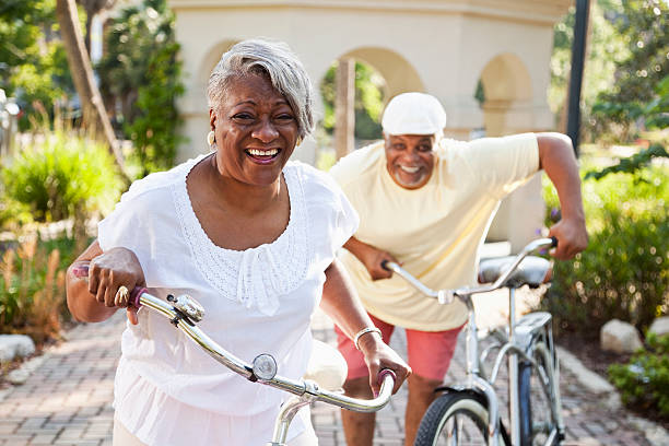 senior coppia afro-americana di biciclette equitazione - senior adult senior couple exercising african ethnicity foto e immagini stock