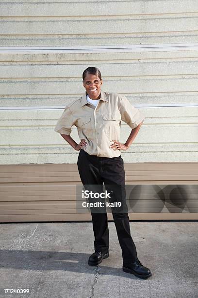Female Worker Standing In Front Of Warehouse Door Stock Photo - Download Image Now - Full Length, Mechanic, One Woman Only