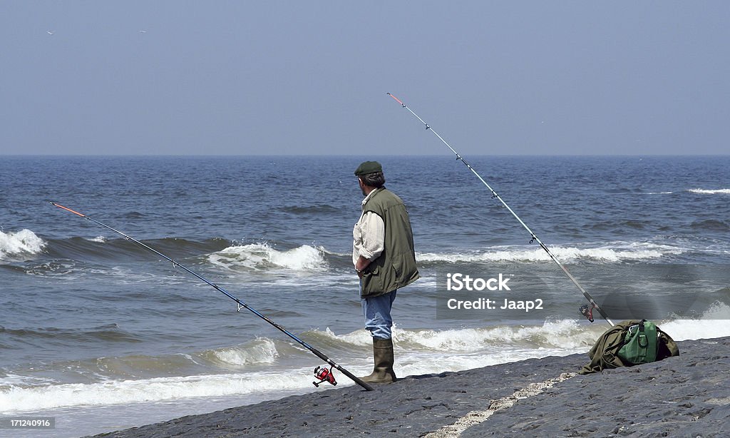 Стоя Рыбак с двумя прутков, рыбалка на море - Стоковые фото Багаж роялти-фри