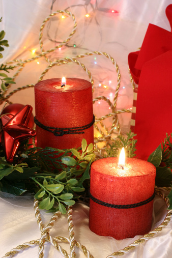 Christmas candles and lights set amid ornaments, gifts and bows.  Photographes with available light for a soft natural look.