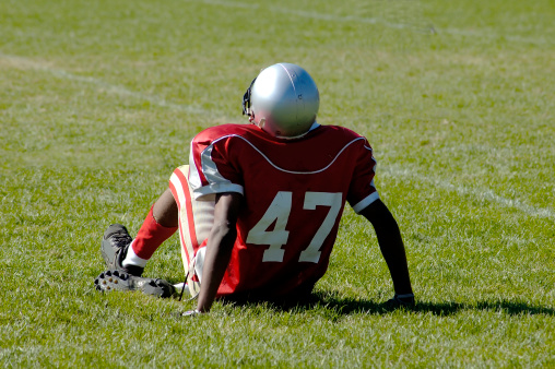 American Football Player sitting on the grass