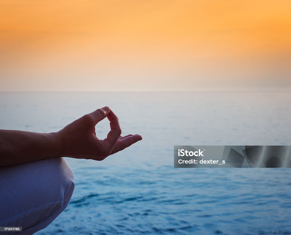 Meditation by the ocean and sky Hand of woman meditating at sunset near the sea. Mindfulness Stock Photo