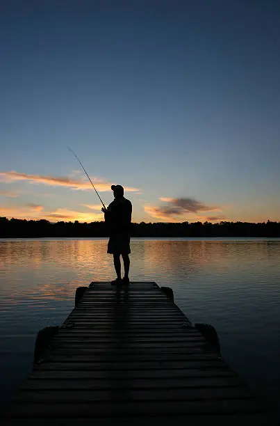 Photo of Silhouette of Retired Senior Fishing off the Dock