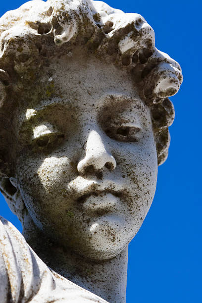 istock Face of young boy, weathered statue against blue sky 171242270