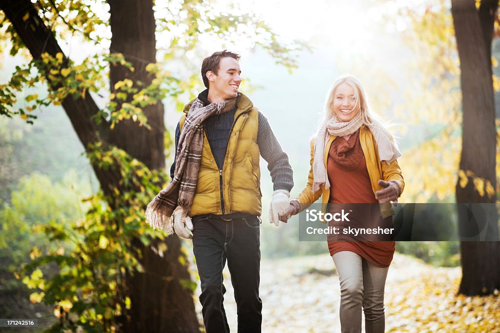 Beautiful smiling couple running in the park Beautiful young couple running in the park on a beautiful autumn day. Active Lifestyle Stock Photo