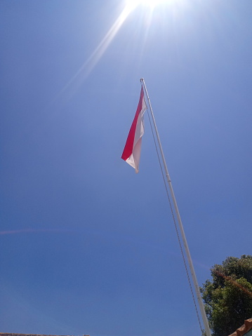 the red and white flag flies on the flagpole