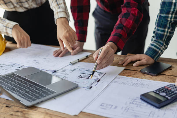 istock Architect interior designer working with home improvement documents for house design Persson Engineer - Hand drawn plans on print with architect equipment. Architects chatting at the table 1712450739