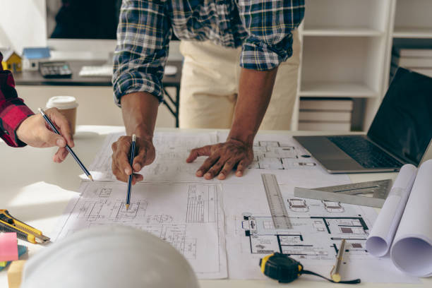 istock Architect interior designer working with home improvement documents for house design Persson Engineer - Hand drawn plans on print with architect equipment. Architects chatting at the table 1712451809