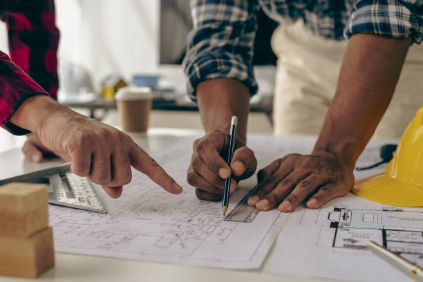 istock Architect interior designer working with home improvement documents for house design Persson Engineer - Hand drawn plans on print with architect equipment. Architects chatting at the table 1712451811