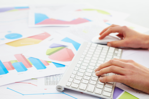 Woman typing on a keybord with charts around her