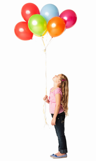 Cute little girl looking up at the bunch of balloons. Vertical shot. Isolated on white.