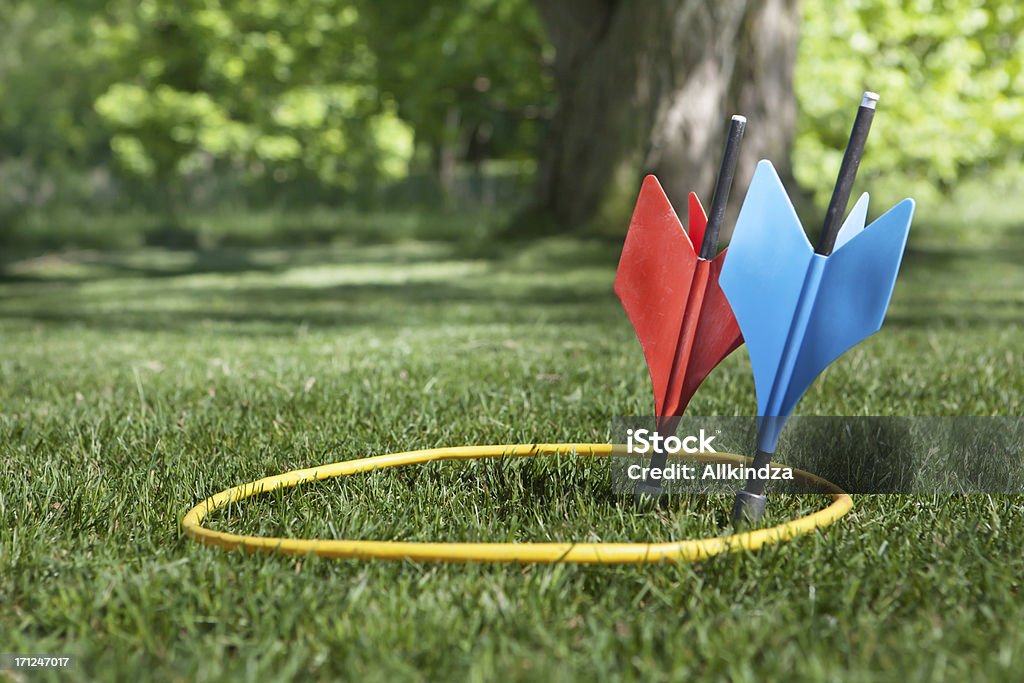 one each on target a shot of some vintage lawn darts somtimes called JARTS. One of each  color inside the yellow ring in a back yard setting. Yard - Grounds Stock Photo