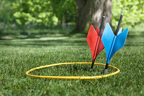 one each on target a shot of some vintage lawn darts somtimes called JARTS. One of each  color inside the yellow ring in a back yard setting. dart stock pictures, royalty-free photos & images