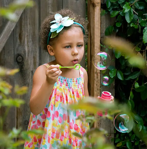 A cute little girl playing with bubbles in her backyard.