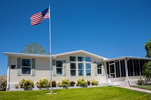 Mobile Home with American Flag Mobile home with American flag, front lawn and clear blue sky. mobile home stock pictures, royalty-free photos & images