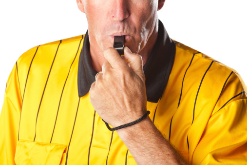 Soccer referee in yellow jersey  blowing whistle