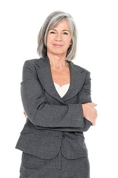 Confident Senior Businesswoman Portrait of a confident senior businesswoman standing with arms crossed isolated over white background. Vertical shot. three quarter length stock pictures, royalty-free photos & images