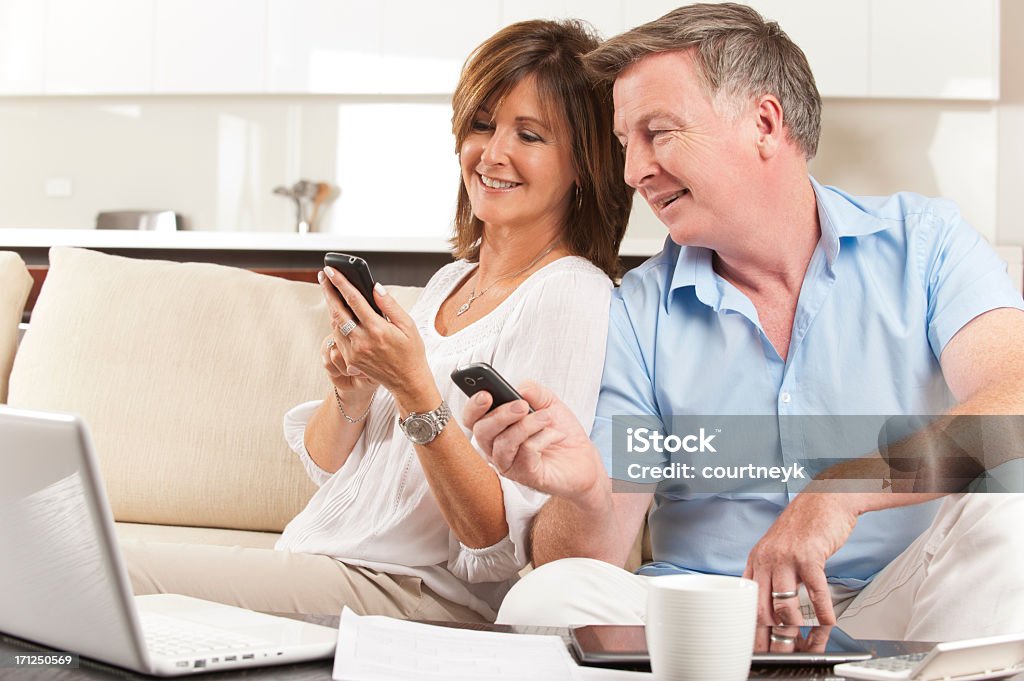 Couple d'âge mûr à la recherche dans chacun d'autres téléphones portables - Photo de Tous types de couple libre de droits
