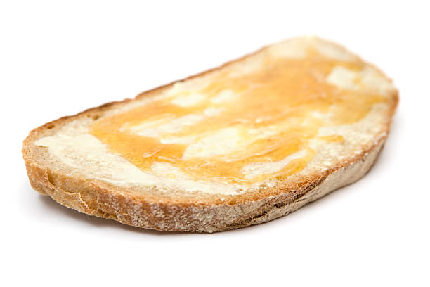 Honey and butter on a slice of bread. Isolated on a white background. Shallow depth of field.