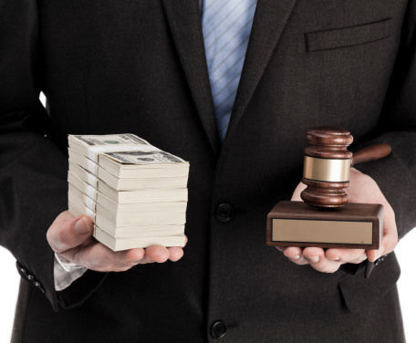 Man in suit holding stack of money and wooden gavel