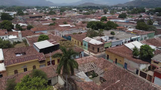 Low aerial flyover of San Salvador city low rise tiled roof tops