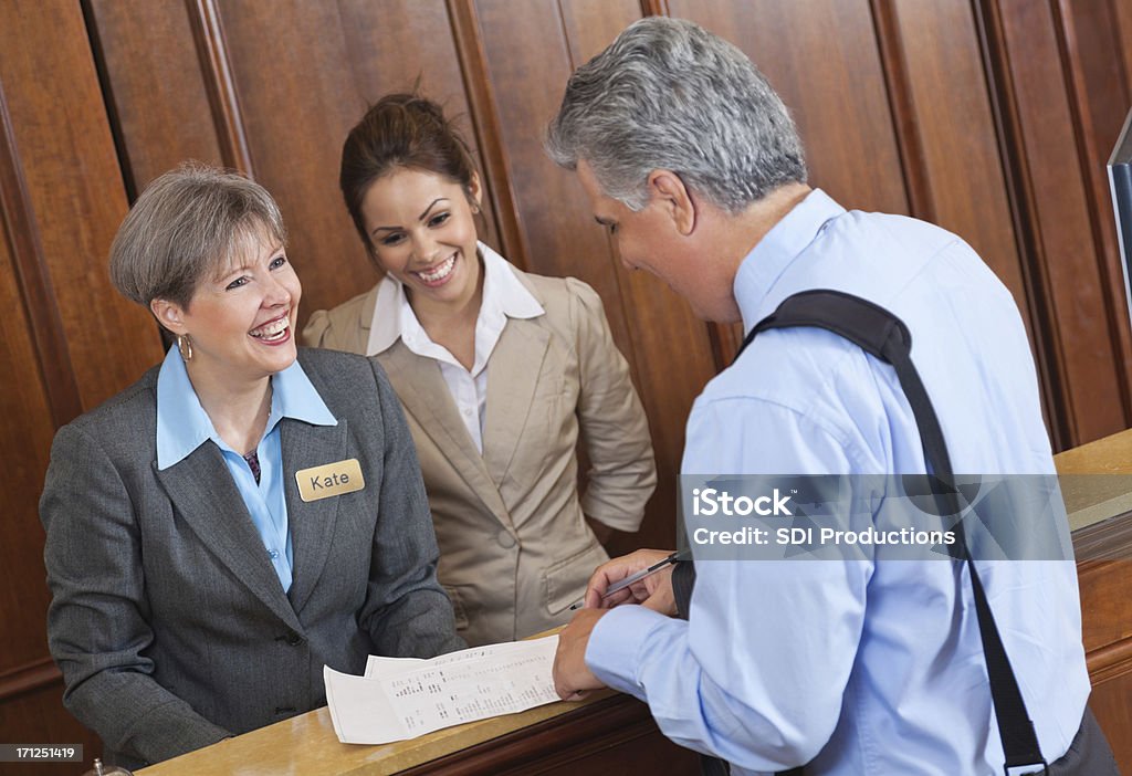 Recepção do Hotel trabalhadores discutir estadia e conta com o hóspede - Foto de stock de Hotel royalty-free