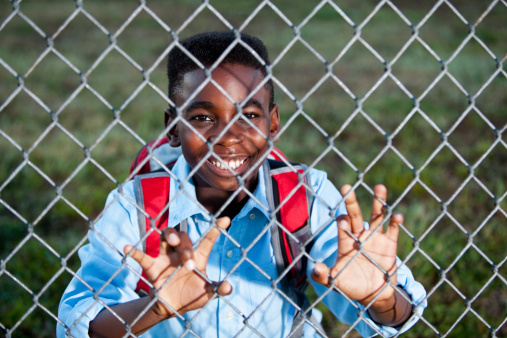 Boy (10 years) looking through chain link fence
